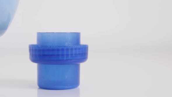 Slow motion fabric softener being poured to container cap close-up video