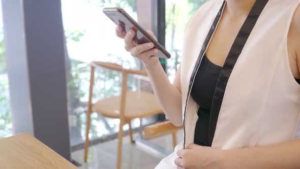 Close up shot of unrecognizable woman working, using smartphone at Cafe