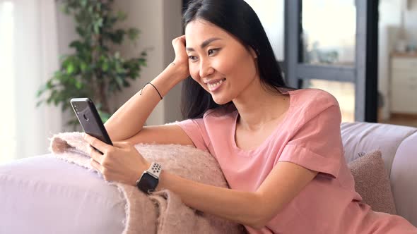 An Attractive Young Asian Woman is Using a Smartphone Indoor