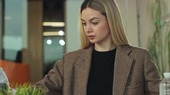 Two Young Female Creatives Sitting in an Office Working Together in Discussion at a Laptop Computer