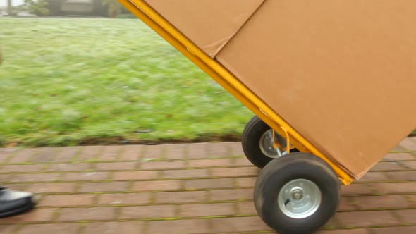 Delivery man pushes dolly full of packages to home