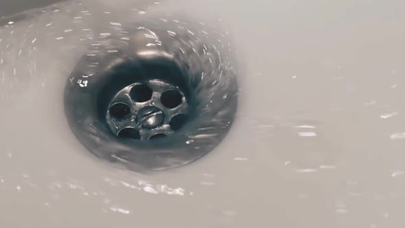 Soapy Water Flowing Down the Drain of a Sink in the Bathroom