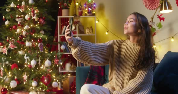 Young Woman Making Selfie on Smartphone Sitting on Sofa in Living Room