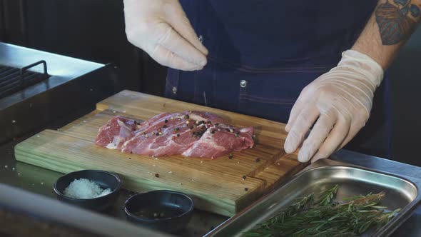 Cropped Shot of a Chef Adding Salt on Pork Meat Before Cooking Steak