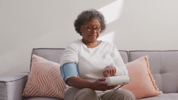 Mixed race woman checking her blood pressure. Social distancing and self isolation in quarantine