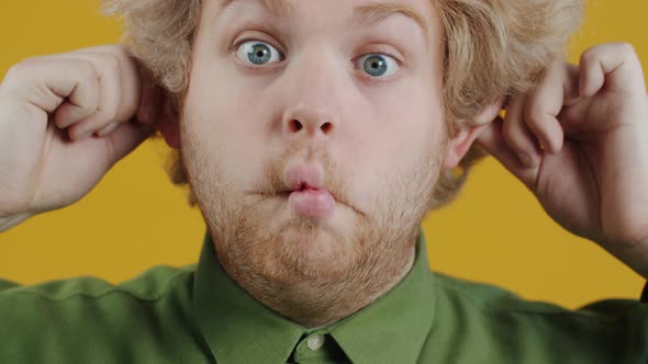 Portrait of Young Man Making Pouting Lips and Funny Eyes and Looking at Camera