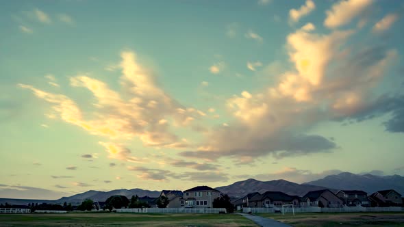 Sunset cloudscape over a suburban neighborhood with mountains in the distance - static time lapse