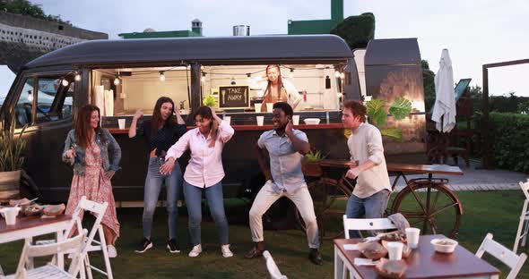 Multiracial people dancing in front of food truck outdoor