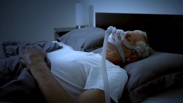 Mature adult sleeping while wearing a CPAP mask