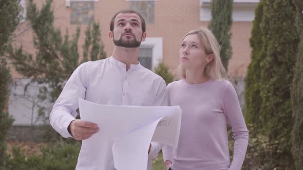 Male Caucasian Bearded Constructor Showing Architectural Drawings To the Customer