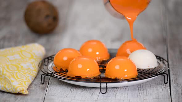 Close up confectioner decorating cakes with mirrored glaze at kitchen