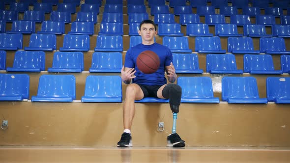 Disabled Basketball Player Sits, Holding a Ball, Close Up