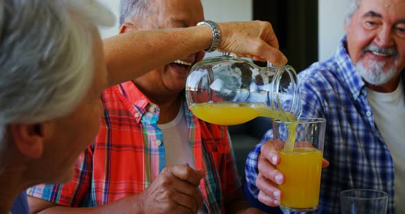 Senior woman pouring juice into glass to her friend 4k