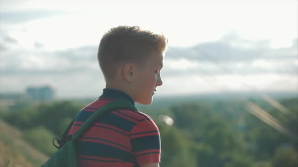 Close Up Portrait Caucasian Boy Teenager in a Red Shirt with a Backpack on His Back, at Sunset