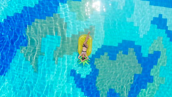 A Lady on the Air Mattress in the Swimming Pool in a Top View