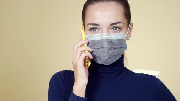 Portrait of Young Woman in Medical Mask Uses Mobile Phone, Isolated Background