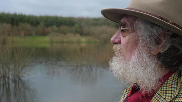 An elderly man looking out over the lake missing the past