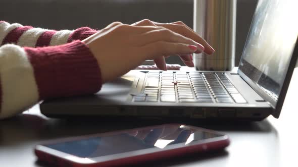 Hands of woman typing on keyboard of laptop