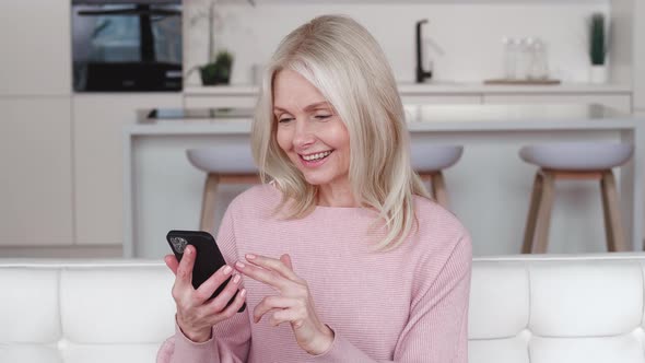 Happy Grey Haired Senior Woman Holding Smart Phone Looking at Cellphone Screen Playing Mobile Games