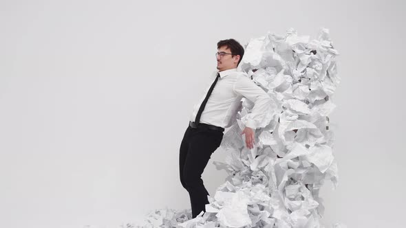 Male Office Worker Tries to Move Mountain of Crumpled Documents Side View