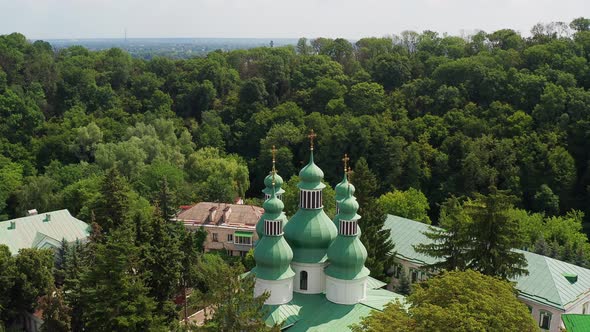 Nice top view of the church. Green domes among the trees. Monastery in the forest.