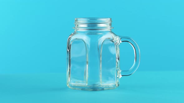  Close-up Shot of Milk Cold Beverage Drink Pooring Into Glass Jar Mug Blue Background in Studio