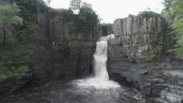Rising up aerial shot of High Force Waterfall in County Durham on dark and moody day