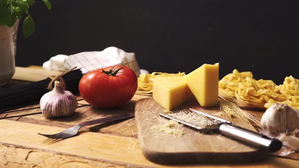 Shredded Cheese with Fresh Basil and Italian Spaghetti on Wooden Kitchen Table