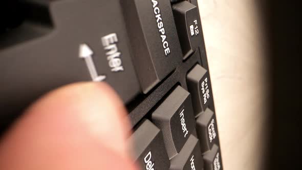 Person Finger Presses Enter Button on Black Keyboard