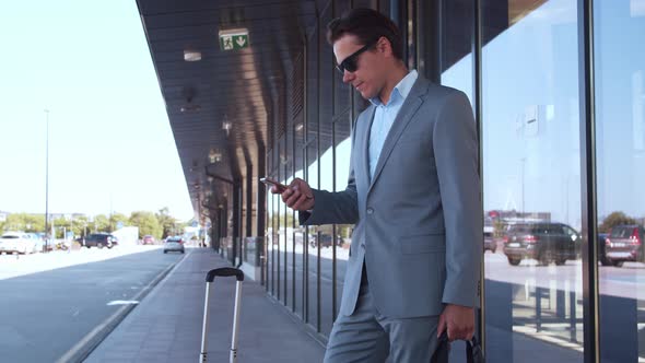 Elegant businessman using smartphone in airport. Young mail entrepreneur.