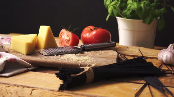 Shredded Cheese with Fresh Basil and Italian Spaghetti on Wooden Kitchen Table