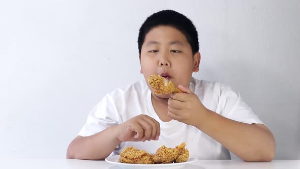 Asian fat boy eats fried chicken Wear a white shirt.