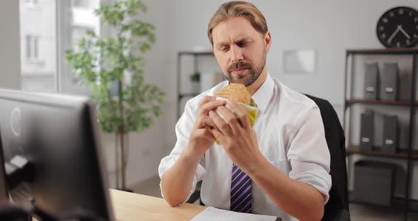 Relaxed Businessman Eating Burger at Office