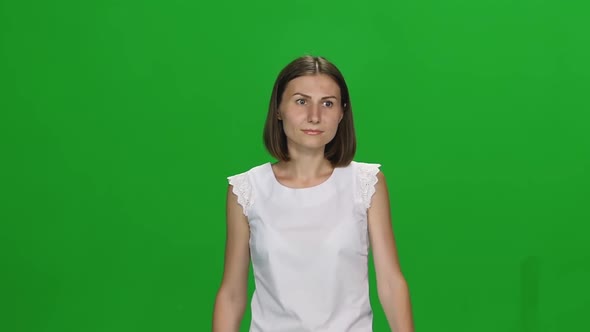 Portrait of Young Woman with Brown Haircut Is Calmly Walking on Green Screen. Chroma Key. Front View