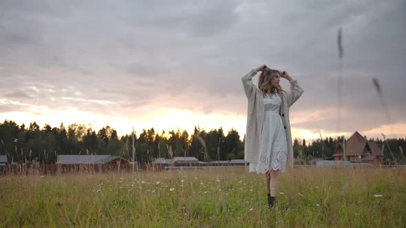 Gentle Woman in White Dress Walking in Rural Field Near Village