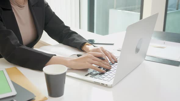 Closeup hands of young woman typing keyboard on laptop computer in the office.