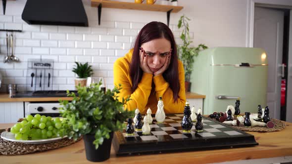 Thoughtful Young Woman Playing Chess Looking for Possible Moves