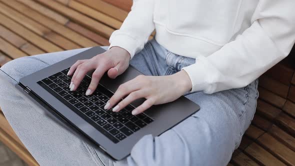 Young Female in Garden Using Laptop Communicates on Internet with Customer