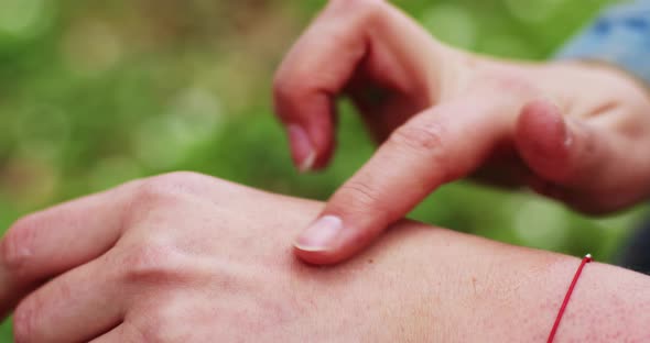 a drop of serum from a glass pipette puts on a woman's hand. fingers rub the organic eco