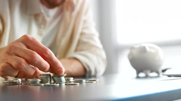 Blurred company manager hand gathers silver coins to stacks on grey table