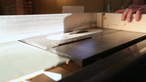 A craftsman rotates and cuts tenons from a piece of wood using a table saw with a dado set in slow m