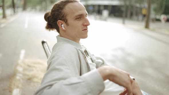 Handsome curly-haired man listening music in headphones