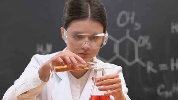 Female Student Adding Liquid to Substance in Flask, Chemical Experiment, Lab
