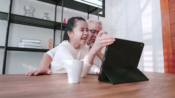 Granddaughter helping grandfather to make video call with family members.