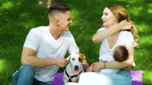 Caring Family with Baby and Dog Spending Leisure Time in Summer Park