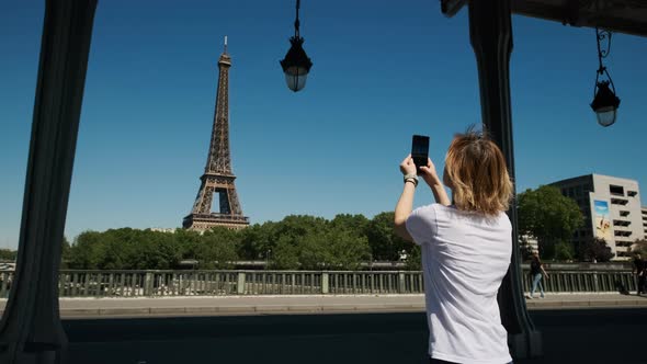 Woman is Taking Selfie Using Smartphone with Eiffel Tower in Paris in Daytime