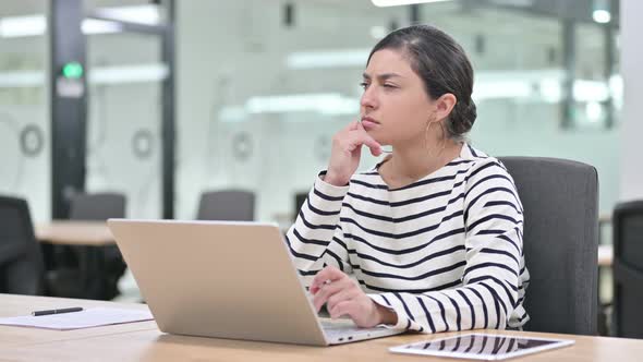 Beautiful Woman Thinking and Working on Laptop in Office 