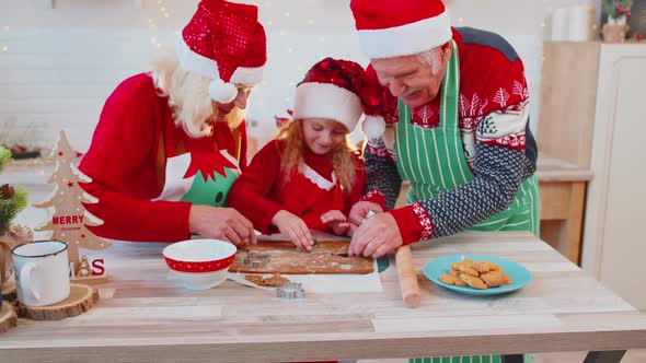 Senior Family Grandparents with Granddaughter in Santa Claus Hats Preparing Cooking Homemade Cookie