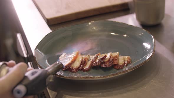 Restaurant Cooking  Chef Burns Slices of Fish with a Burner