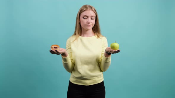 Young Woman Choosing Between Apple and Cupcake, the Girl Is Confused in Her Choice